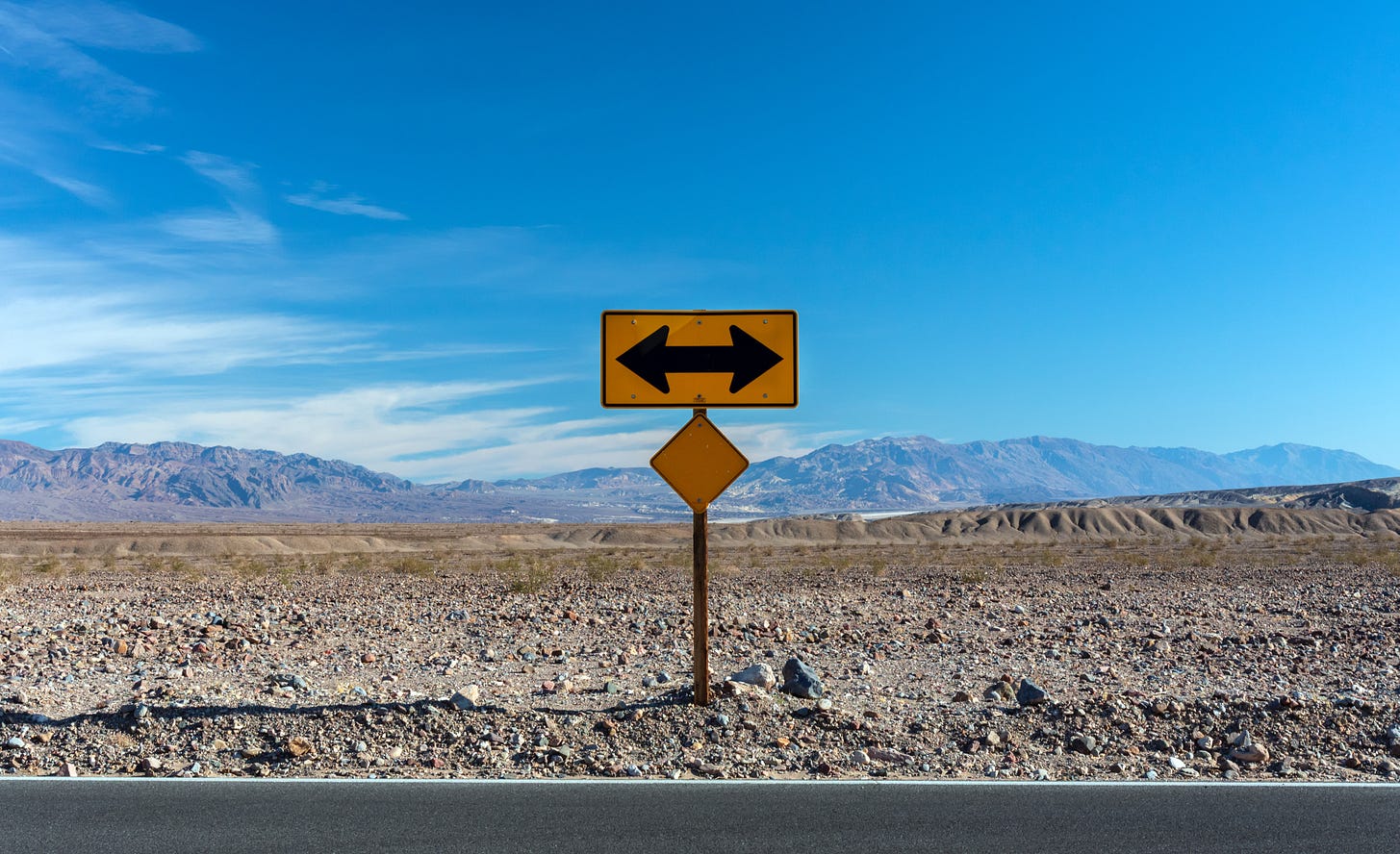 road sign with two arrows pointing to the left and right in the desert